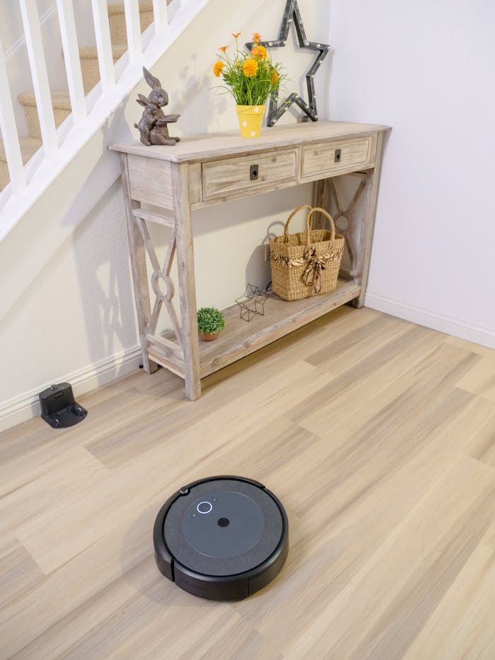 A sleek robotic vacuum navigating a stylish room with a wooden console table and decor.